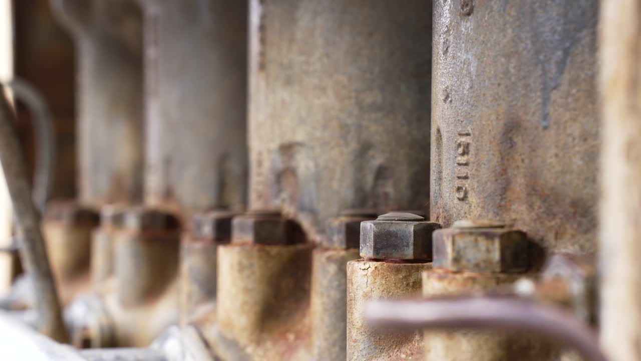 Industrielle motordele der viser detaljer, rust og metalskruer i nærbillede.