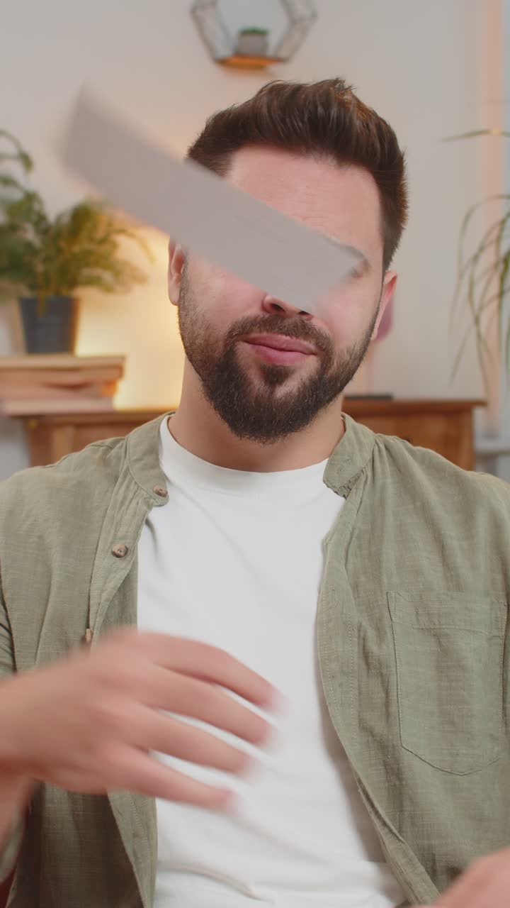 joven caucásico estresado sentado en el sofá revisando facturas de deuda no pagadas y vomitando en el aire