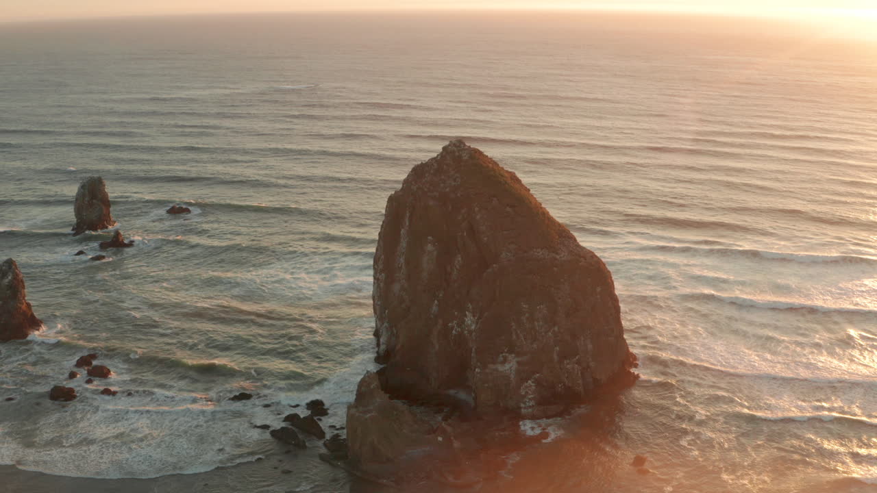 toma aérea en círculo de una pila de rocas de heno, una pila de mar al atardecer