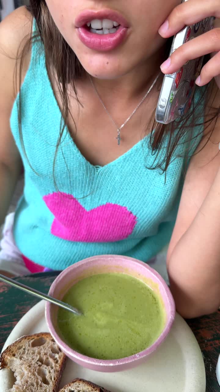Woman Eating Soup and Talking on the Phone