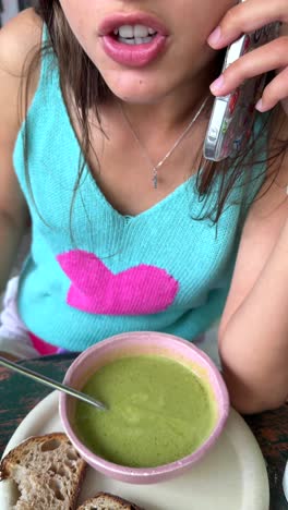 woman eating soup and talking on the phone
