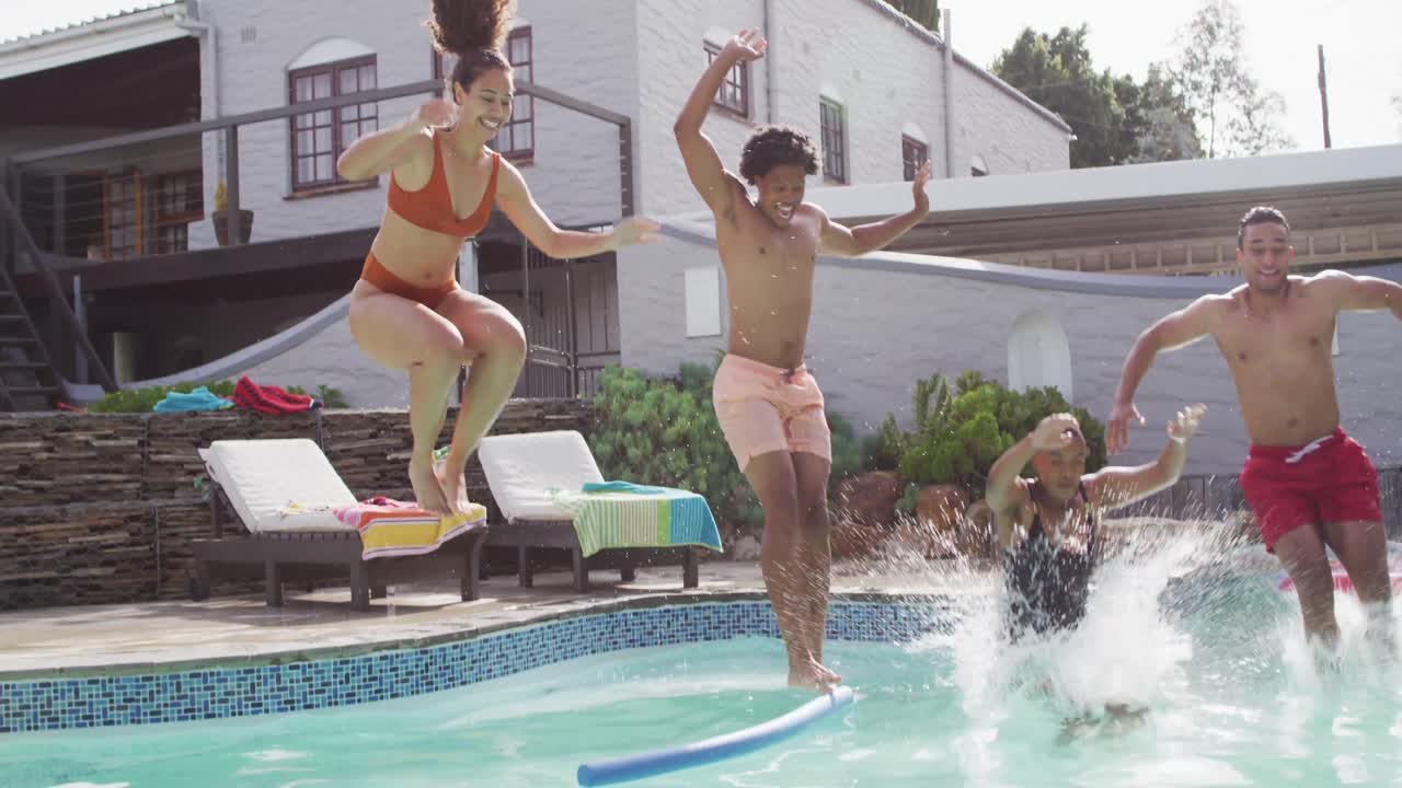 grupo de felices y diversos amigos femeninos y masculinos saltando a la piscina en una fiesta en la piscina