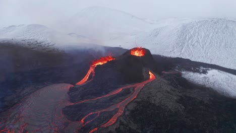 vista aérea alrededor de las fuentes de lava del volcán, en medio de la naturaleza nevada - órbita, disparo de drones