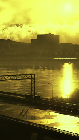 golden sunset reflection over river with city skyline and highway