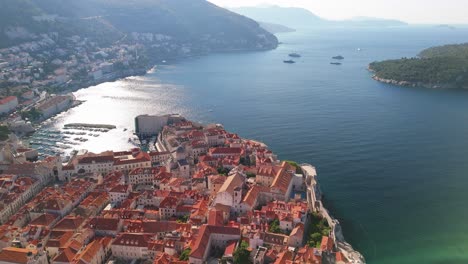 Cinematic-aerial-drone-flight-over-Dubrovnik,-Croatia-with-old-town-city-walls-glistening-in-the-morning-sunshine