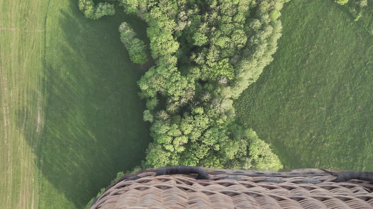 Flying over fields and trees in hot air balloon, down view with a basket, great cinematic shot with emotions of the moment in the air