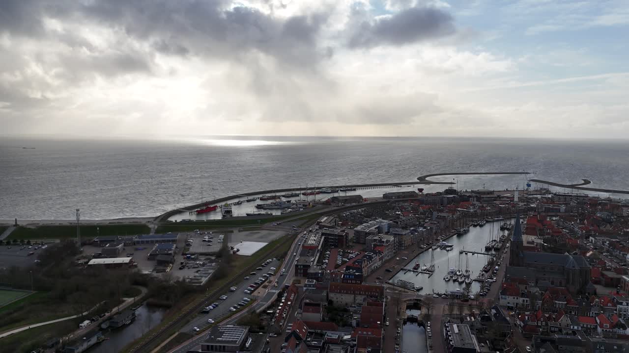 Statisk luftoptagelse af havnekonstruktioner og hav med kirkesilhuet i forgrunden