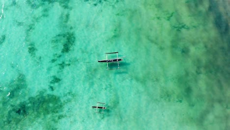 aerial view of a fisherman sails on a wooden boat on clear blue water along a tropical exotic beach in africa