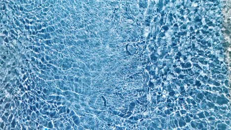 Water-surface-texture,-Slow-motion-looping-clean-swimming-pool-ripples-and-wave,-Refraction-of-sunlight-top-view-texture-sea-side-white-sand,-sun-shine-water-loop-background