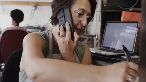 Busy-caucasian-female-worker-talking-on-smartphone-in-jewellery-studio-in-slow-motion