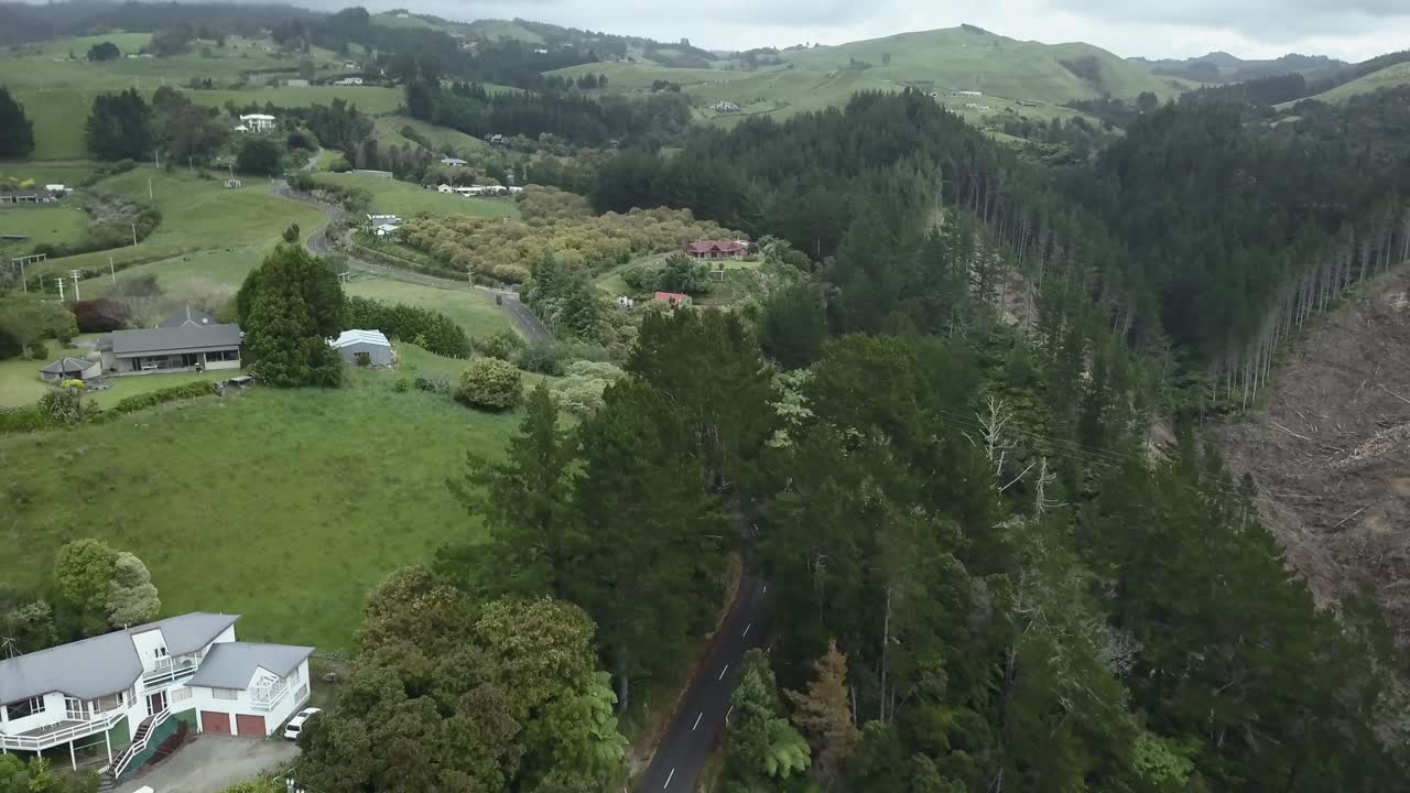 Aerial view of a rural landscape with hills, forest, road, and houses