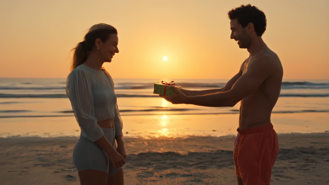 Couple exchanging a gift on a beach at sunset