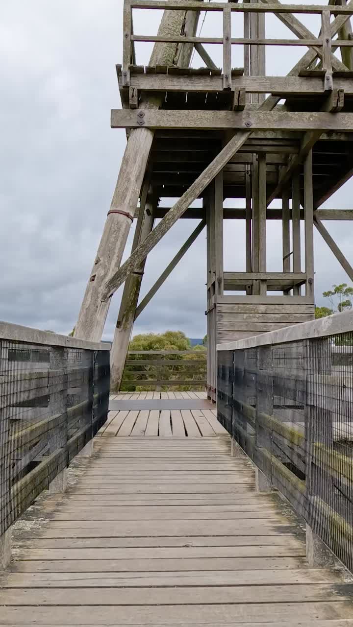 un paseo constante a lo largo de un puente de madera que conduce a una torre de observación, que muestra la arquitectura rústica y las vistas panorámicas en ballarat, australia