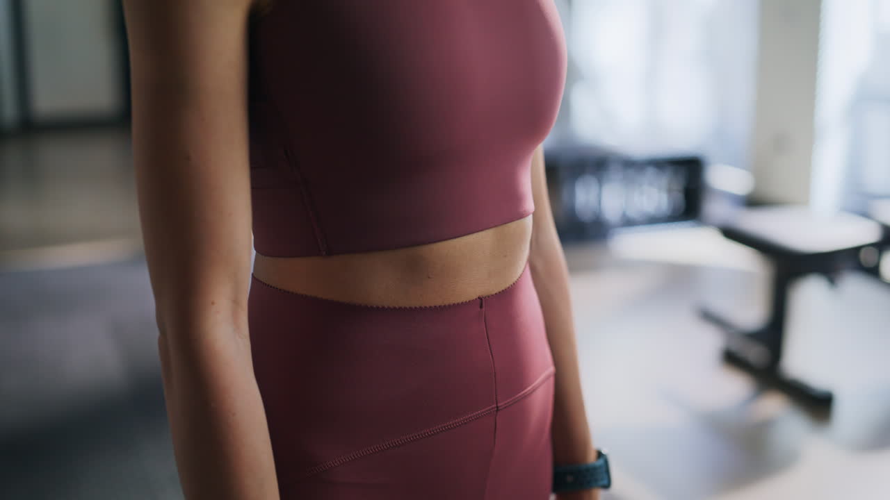 Woman athlete checking smartwatch standing in gym closeup. Sportswoman smiling