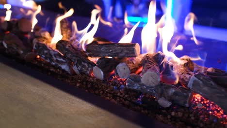 camera truck left slowly of fire flames in a modern fireplace, indoor at night with purple lighting background, close up in slow motion