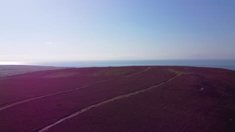 aerial drone shot from rhossili down with peak marker before revealing ocean view in background from moorland 4k