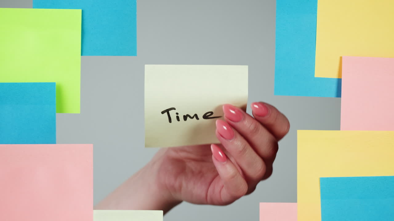 Hand Removing 'Time' Sticky Note from Grey Background
