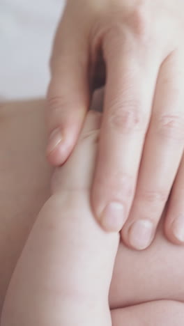 restless newborn boy with fair hair cries lying on changing table and nurse practices stomach massage close view