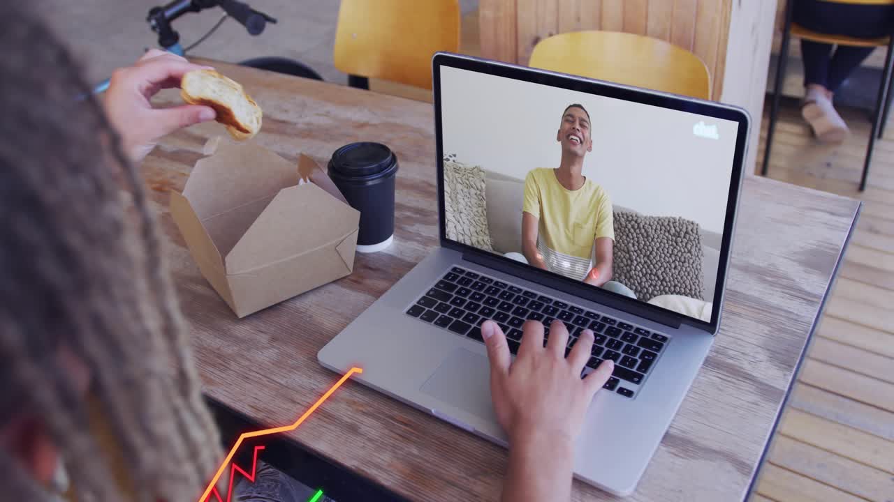 Local user typing on laptop and taking bite of bagel, causing animated graphs during business call