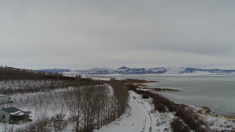 Volando-Sobre-Una-Granja-Cerca-De-La-Costa-Del-Lago-Utah-Cerca-De-La-Playa-De-Lincoln,-Mirando-Hacia-Las-Montañas-Del-Oeste-Vistas-Por-Drones