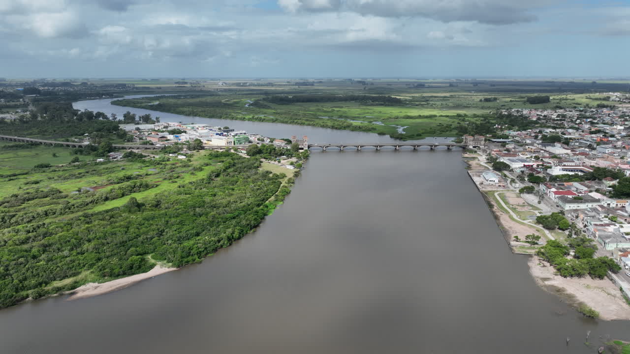 Panorama cinematografico ad alta quota che mostra le città di Jaguarão in Brasile e Rio Branco in Uruguay, collegate dallo storico ponte internazionale Mauá sul fiume al confine