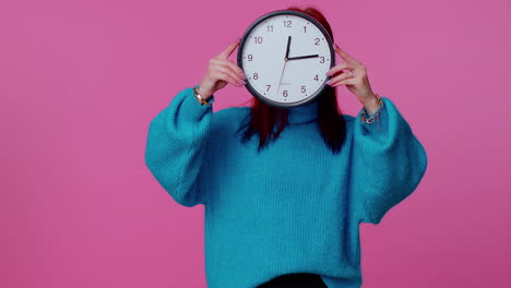 young woman holding clock watch, hiding, checking time on clock, running late to work being in delay