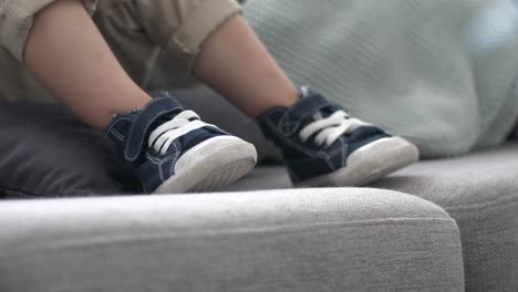 cute child shoes on sofa, blue sneakers on gray sofa, close up