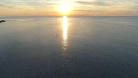 person paddle boarding in the ocean at sunset