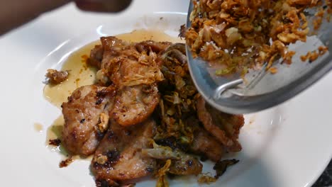 la mano asiática agrega ajo frito sobre el ajo salteado y el cerdo con pimienta, cierra, en cámara lenta, de mano