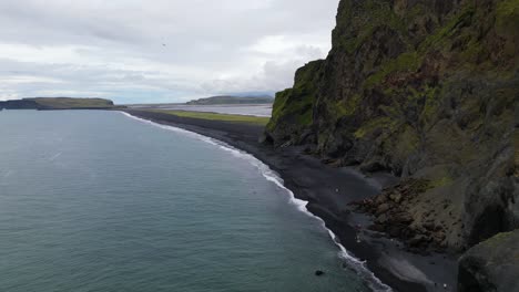 Reynisfjara-Schwarzer-Sandstrand-In-Wunderschöner-Isländischer-Landschaft,-Drohnenflug-Aus-Der-Luft