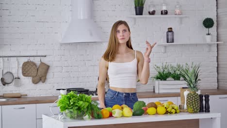 young woman with fresh vegetables and fruit indoors. vegetarian female eating organic food in the modern kitchen at home. dieting concept.
