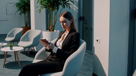businesswoman using mobile phone in office waiting area