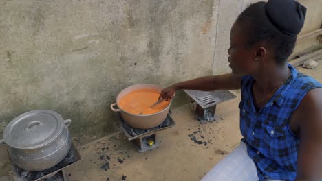 Fufu-Ist-Eine-Zerstampfte-Mahlzeit,-Die-In-Der-Westafrikanischen-Küche-Vorkommt,-Nahaufnahme-Einer-Schwarzen-Ghanaischen-Frau,-Die-Das-Essen-In-Einem-Topf-Auf-Der-Straße-Zubereitet