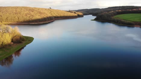 Toma-Aérea-Hacia-Atrás-Del-Lago-Wimbleball-Exmoor-Destacando-Las-Asombrosas-Aguas-Tranquilas-Del-Lago-Y-El-Reflejo-Del-Cielo