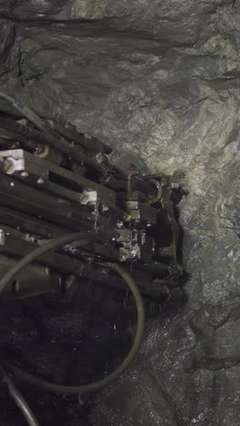 professional equipment drills holes in rocks of ore mine spraying water. robot machinery with coolant operates to extract natural resources closeup