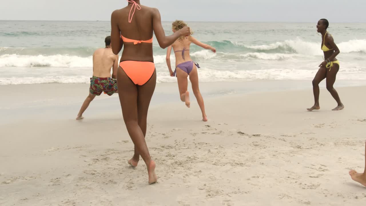 группа друзей смешанной расы играет в летающий диск на пляже 4k