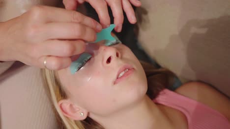 Eye-lash-artist-carefully-combs-lashes-to-the-mould-of-teenage-child-model