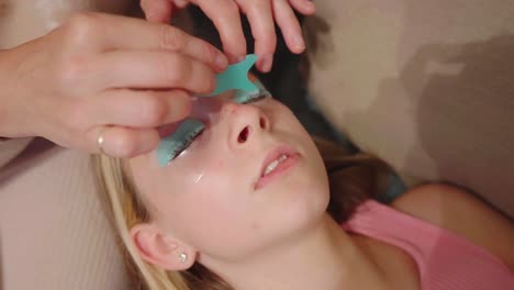 eye lash artist carefully combs lashes to the mould of teenage child model