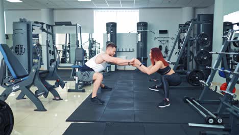 couple during exercise class at the gym. close up of focused and motivated strong young fitness couple in sportswear doing squats in the gym