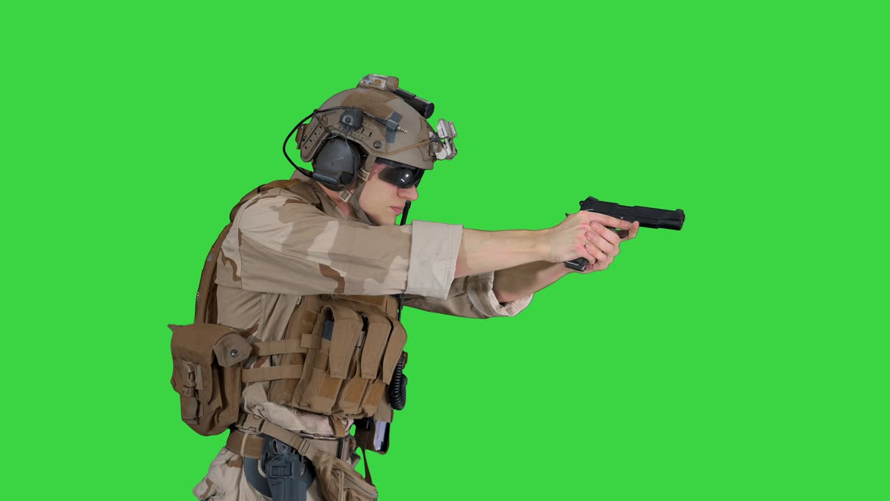 морской пехотинец в камуфляже идет и нацеливается с ручным пистолетом на зеленый экран, хроматический ключ