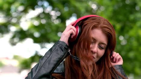 pretty redhead listening to music in the park