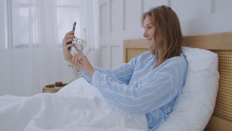 businesswoman having a video call in hotel. happy girl lies on the bed talks with friends via video call.