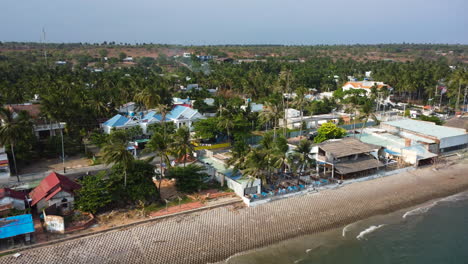 Aerial-backwards-view-of-houses-in-front-of-sea-with-a-wall-as-protection