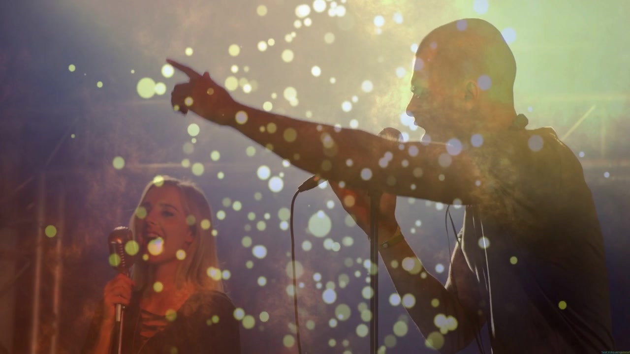 Forsanger starter og gestikulerer, korsanger harmoniserer, mens bokeh omgiver sangerne til musik.