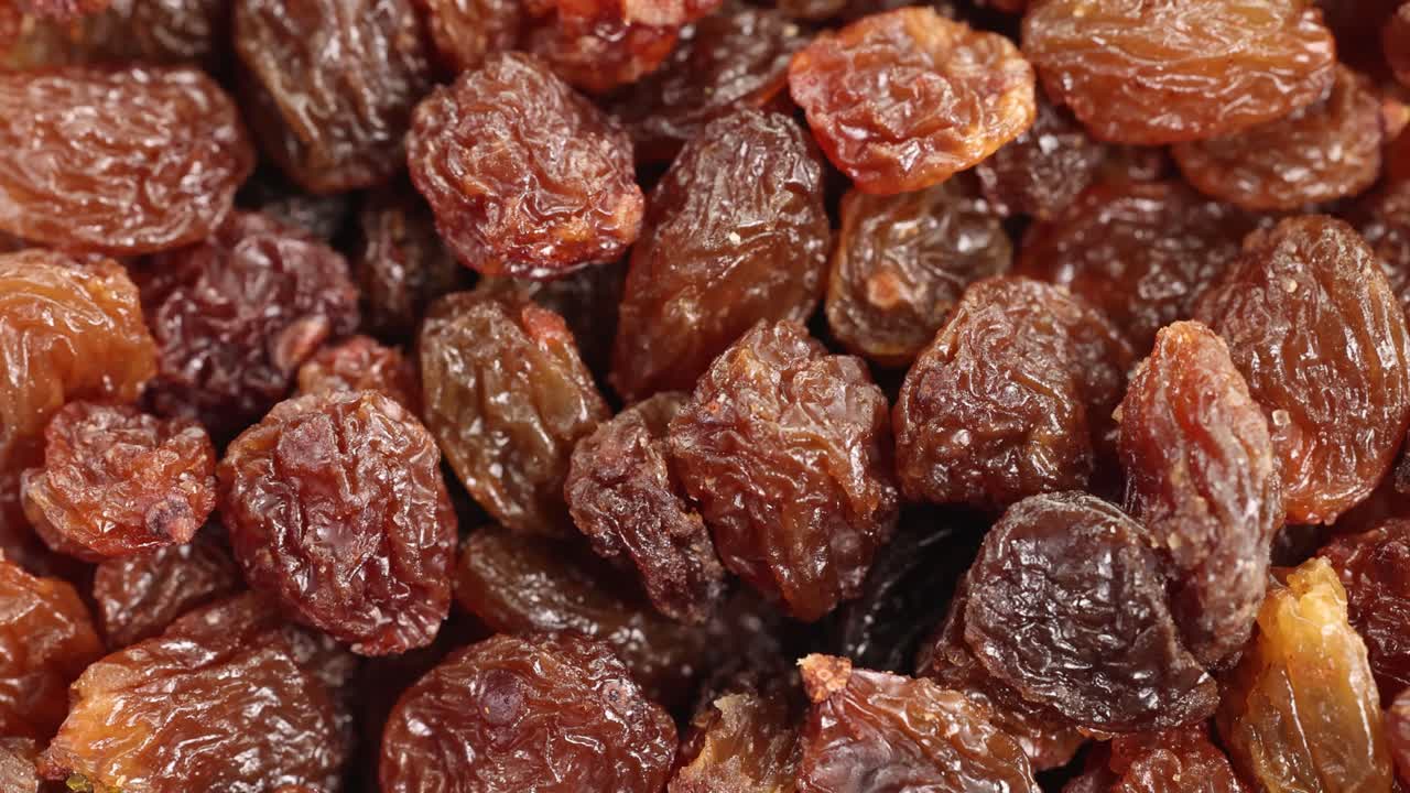 Passas caem em cascata em uma pilha em uma visão macro detalhada, destacando variações de textura e cor sob iluminação suave.