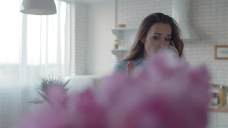 Mujer-Concentrada-Hablando-Por-Teléfono-En-La-Cocina.