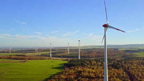 Kamera-Fliegt-Langsam-über-Einen-Herbstlichen-Wald-Mit-Blick-Auf-Majestätische-Windräder-Zwischen-Den-Bäumen-–-Gefilmt-In-4k