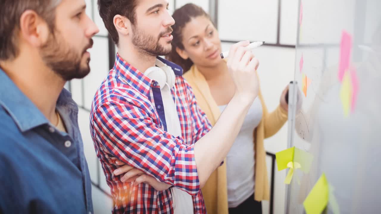 video de creativos diversos colegas masculinos y femeninos escribiendo en notas de memoria en la oficina moderna