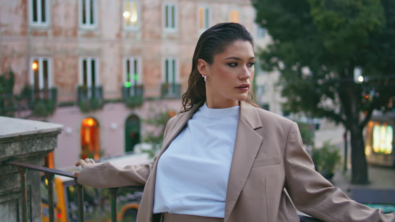 беспечная девушка отдыхает на городской улице, опираясь на перила вблизи.