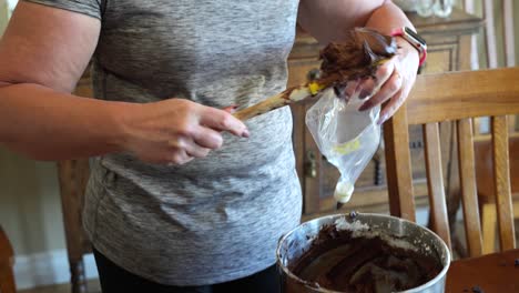 scooping chocolate frosting into an icing bag to